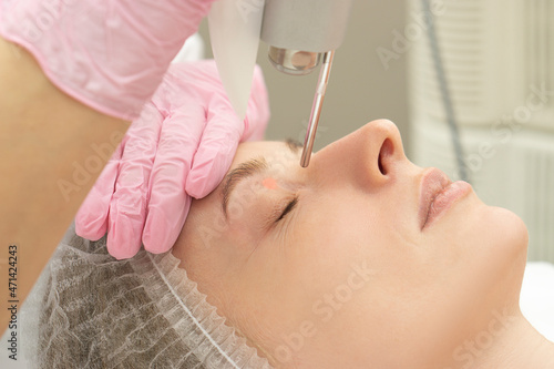 Obraz na płótnie close-up Doctor cosmetologist makes the procedure of laser dermal rejuvenation of the eyelids of the skin around the eyes to the patient