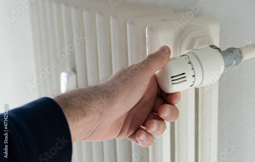 Hand on the valve of heating radiator.