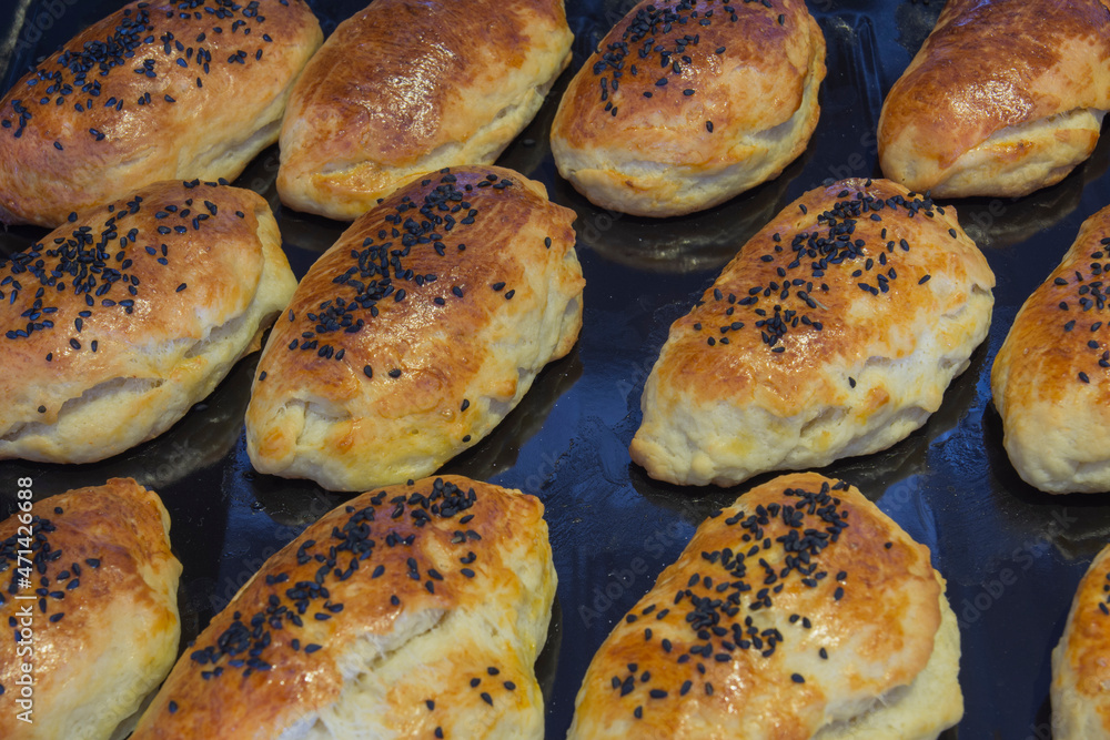 Homemade pastries that are brushed with egg yolk and sprinkled with black cumin. selective focus. on the baking tray Homemade pastries that are brushed with egg yolk and sprinkled with black cumin. selective focus. on the baking tray