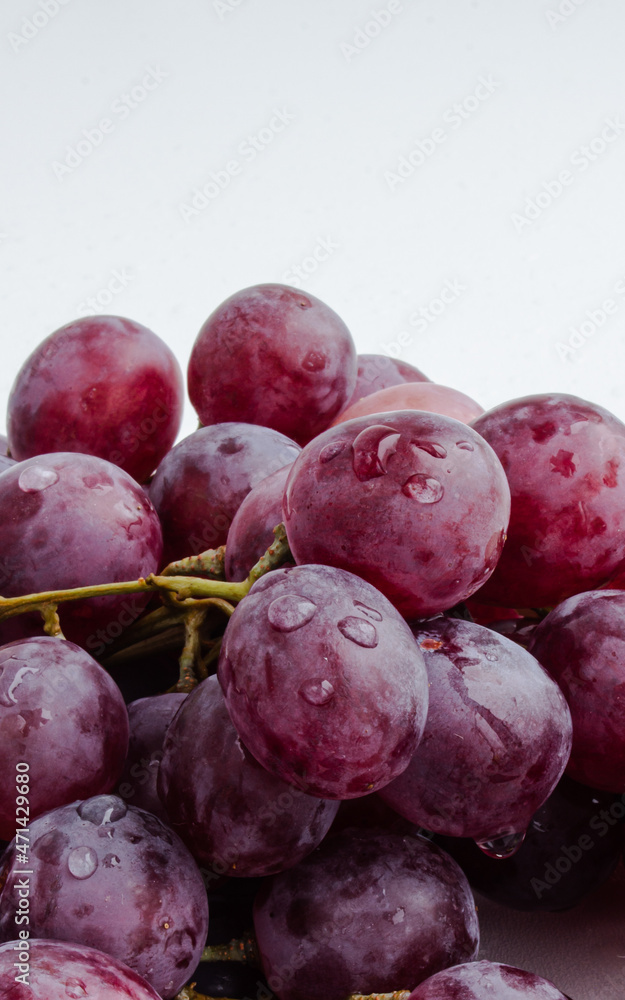 Purple grapes on a white background with drops on the fruits Purple grapes on a white background with drops on the fruits