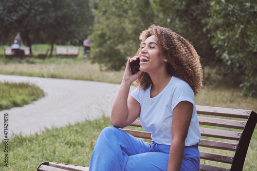 A beautiful african american woman talks on the phone with friends or colleagues, relaxes, enjoys remote communication. Solving business problems and provide customer service via mobile outdoor.