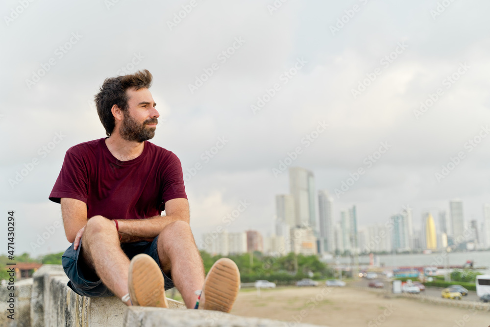 Side view of man traveling in Cartagena de Indias. Horizontal view of wanderlust man traveling with Bocagrande skyline in the background. Travel to Colombia concept.