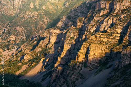 Cliff and rocks of the mountains create an amazing pattern illuminated by the rays of the setting sun. The play of light and shadow