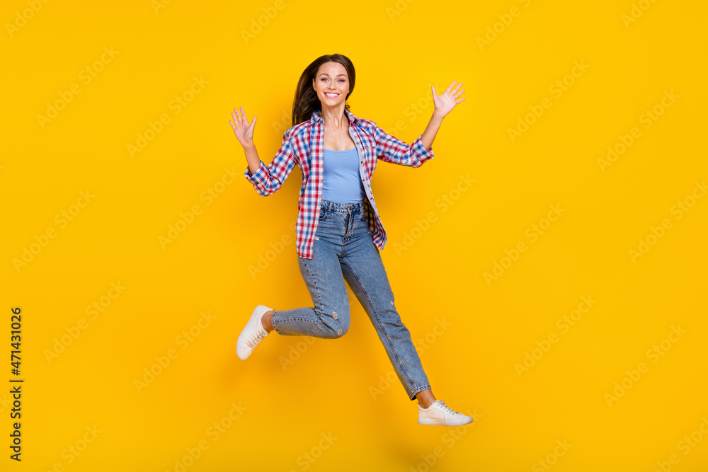 Full length photo of crazy lady jump raise hands hurry run wear plaid shirt jeans shoes isolated yellow color background