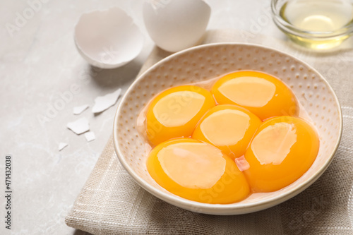 Bowl with raw egg yolks on light grey table