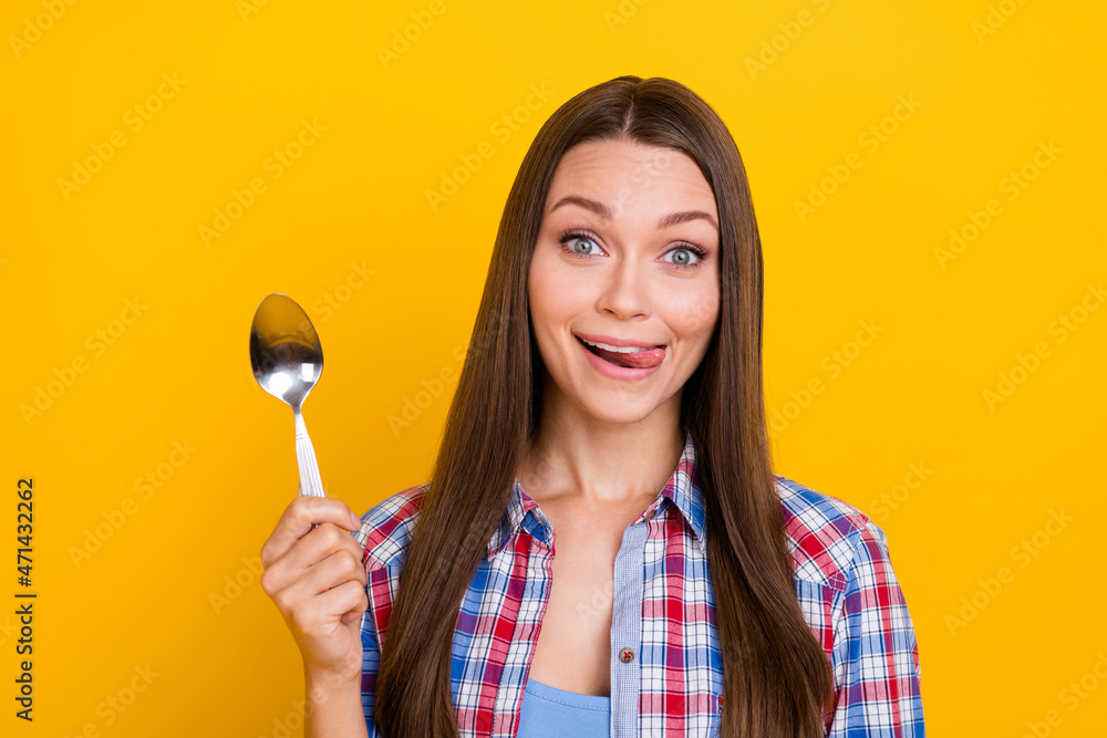 Photo of cheerful lady hold silver spoon stick-out tongue wear checkered shirt isolated yellow color background Photo of cheerful lady hold silver spoon stick-out tongue wear checkered shirt isolated yellow color background