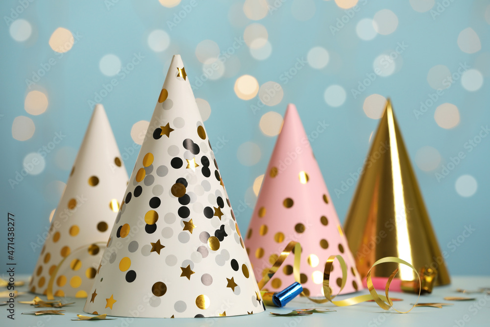 Party hats and festive items on table against blue background with blurred lights Party hats and festive items on table against blue background with blurred lights
