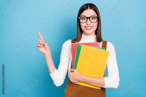 Photo of young cheerful girl indicate finger empty space teacher ads choose isolated over blue color background