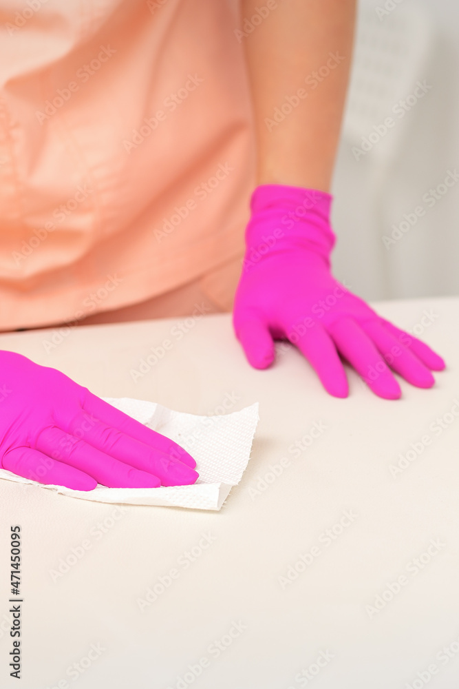 Close up of hands in rubber protective pink gloves cleaning the white surface with a white rag Close up of hands in rubber protective pink gloves cleaning the white surface with a white rag