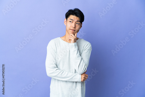 Young Chinese man isolated on purple background having doubts and thinking