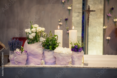 Close up view flower bags with white candles burning on altar. Church interior and set up on catholic weddings ceremony