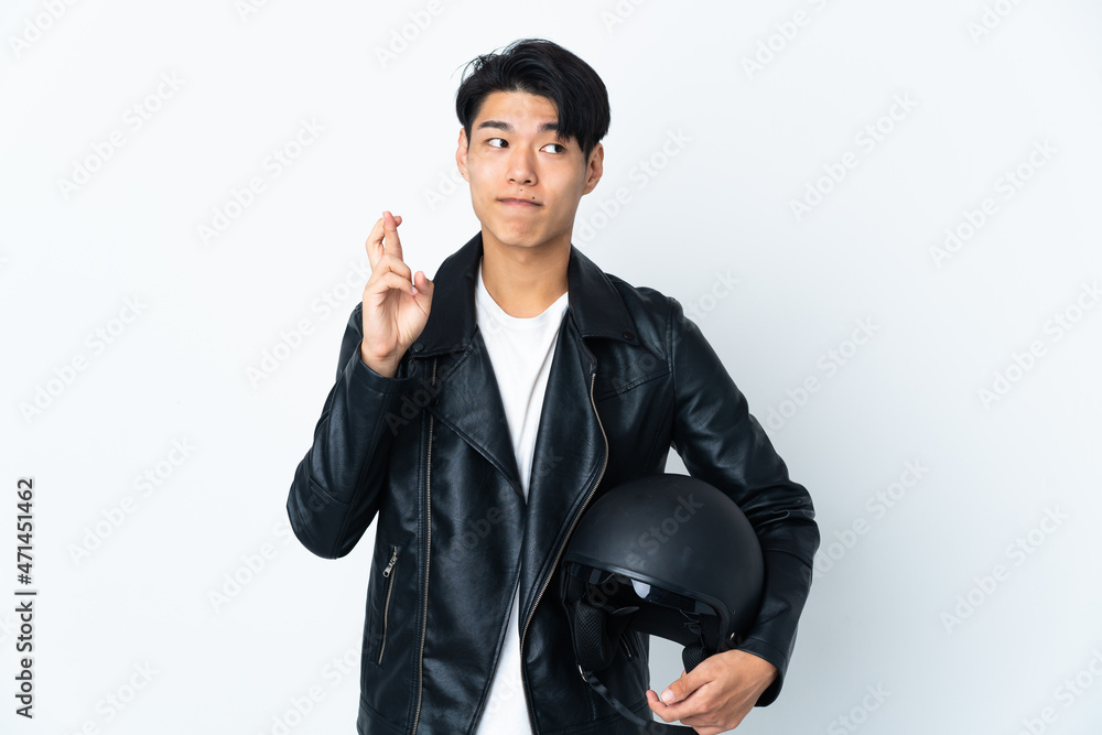 Chinese man with a motorcycle helmet isolated on white background with fingers crossing and wishing the best