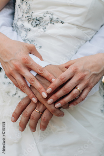 Close up detail of female and male hands of newlyweds at weddings displaying gold wedding rings