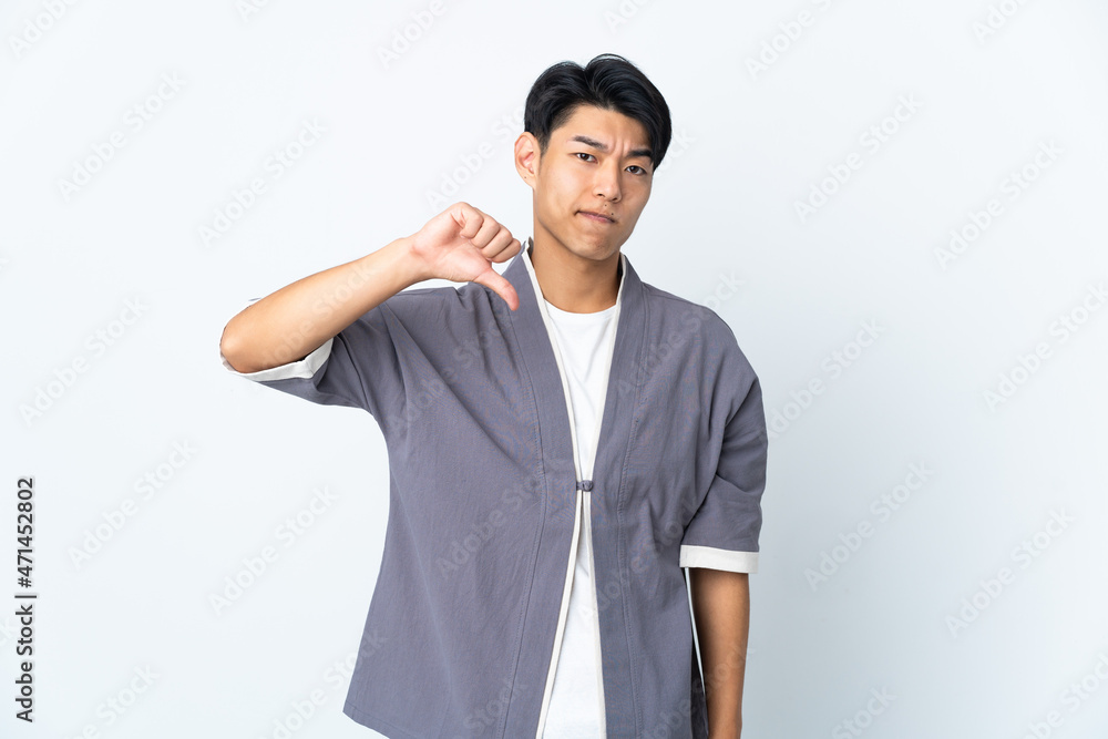 Young Chinese man isolated on white background showing thumb down with negative expression Young Chinese man isolated on white background showing thumb down with negative expression
