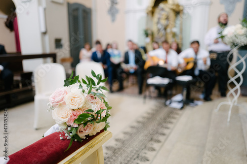 Bride bouquet on cushion with out of focus background musicians group perform in church in traditional wedding ceremony