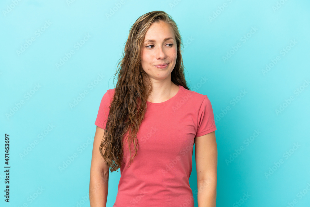 Young caucasian woman isolated on blue background having doubts while looking side Young caucasian woman isolated on blue background having doubts while looking side