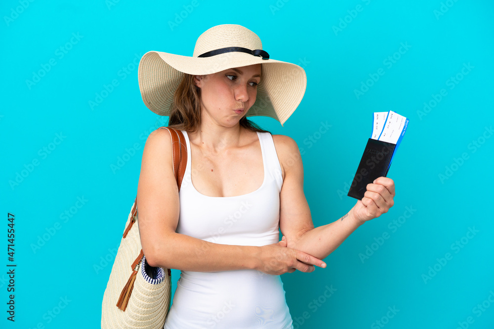 Young caucasian woman holding a beach bag and passport with pamel isolated on blue background with sad expression Young caucasian woman holding a beach bag and passport with pamel isolated on blue background with sad expression