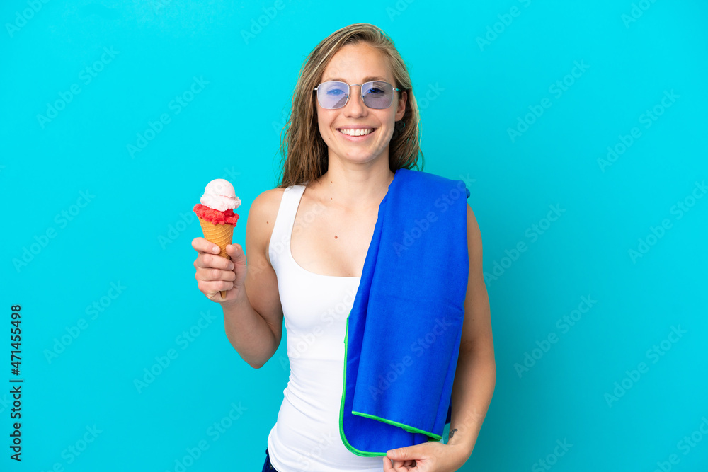 Young caucasian woman holding ice cream and wearing a beach towel isolated on blue background smiling a lot Young caucasian woman holding ice cream and wearing a beach towel isolated on blue background smiling a lot