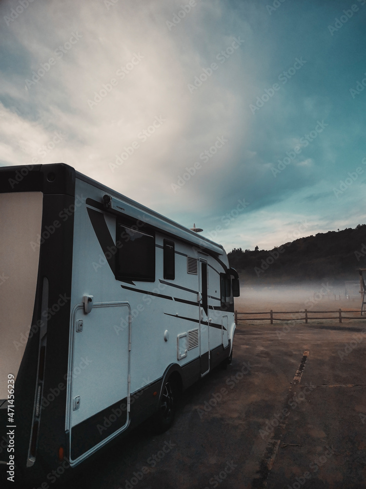 Rv vehicle camper van parked in the nature with fog and beautiful blue sky in background. Concept of travel people and adventure vacation