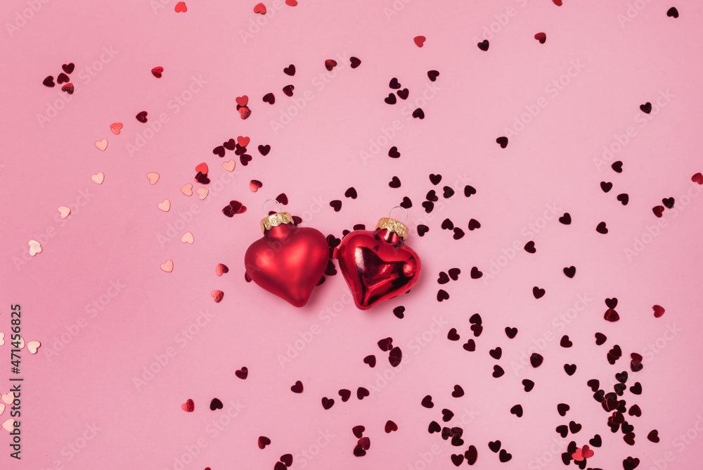 Red confetti in the form of hearts on a pink background and Decoration Valentines day backdrop Flat lay style with minimalistic design Template for banner or party invitation