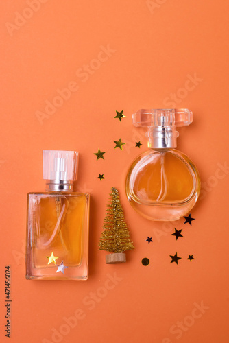 Different Perfume Bottles with Golden Christmas Tree and Golden Confetti on Orange Background Holiday Christmas Gift Concept Vertical Minimal