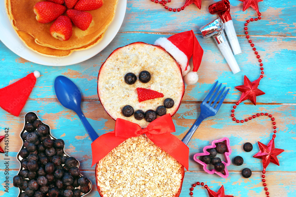 Funny oatmeal snowman with blueberry smile and strawberry nose.
Festive idea for kids breakfast. New Year Christmas food top view. holiday, celebration, food art