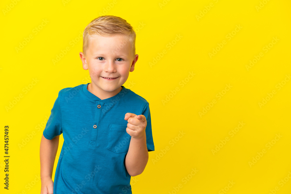Little Russian boy isolated on yellow background pointing finger to the side and presenting a product Little Russian boy isolated on yellow background pointing finger to the side and presenting a product