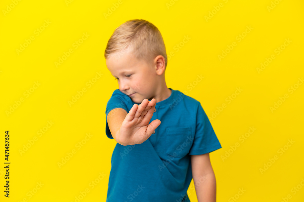 Little Russian boy isolated on yellow background making stop gesture and disappointed Little Russian boy isolated on yellow background making stop gesture and disappointed