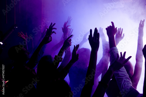 Photo of cheerful bachelors millennial fellows enjoy famous celebrity music raise hands up on disco event with violet neon light