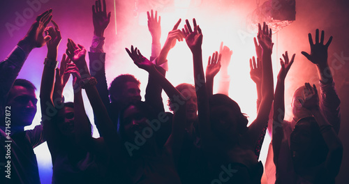 Photo of rejoice youngsters having corporate disco occasion dance raise hands up on discotheque with colorful modern lights