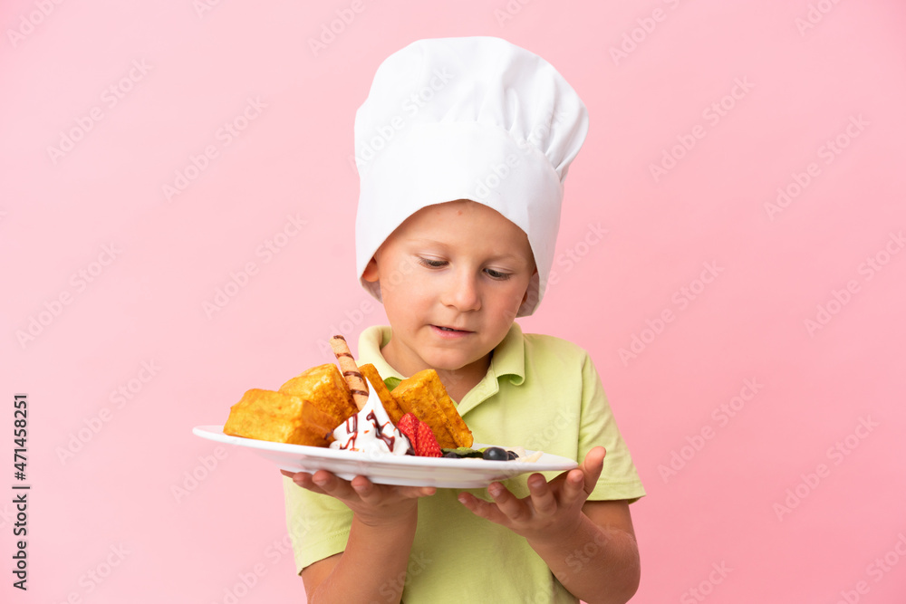 Little Russian boy holding waffles over isolated background Little Russian boy holding waffles over isolated background
