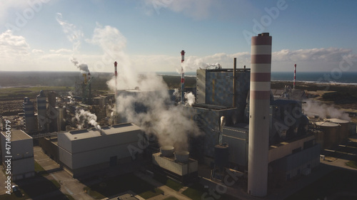 Massive amount of steam ejected into air in huge factory facilities, aerial drone view