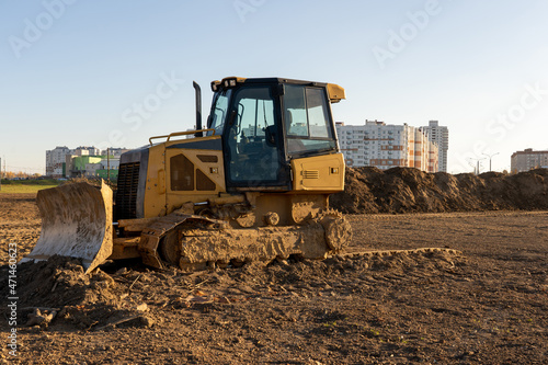 Photo of a yellow muddy excavator digging the ground at a construction site. Constructional concept