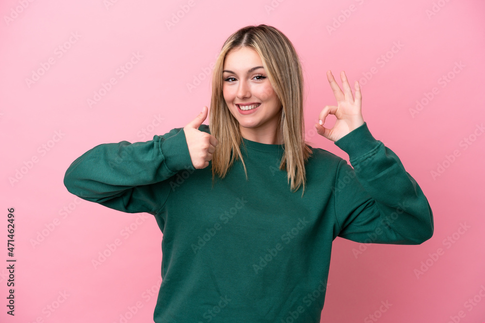 Young caucasian woman isolated on pink background showing ok sign and thumb up gesture Young caucasian woman isolated on pink background showing ok sign and thumb up gesture