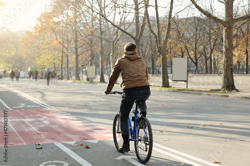 Fototapeta Naklejka Na Ścianę i Meble -  Man riding bicycle on lane in city, back view