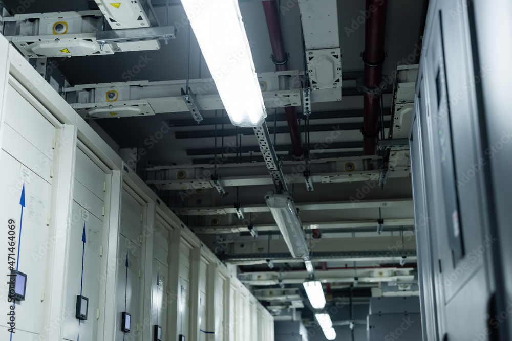 low angle view of closed servers in data center with fluorescent lamps, cyber security concept