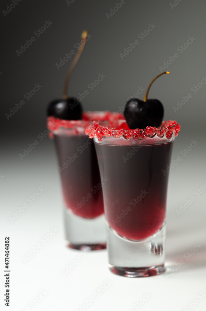 Ruby red cocktail based on vodka, cherry liqueur and syrup in drink shot glass, decorated with fresh cherry and red sugar Ruby red cocktail based on vodka, cherry liqueur and syrup in drink shot glass, decorated with fresh cherry and red sugar