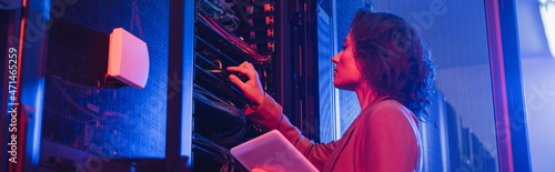 Obraz na płótnie engineer holding digital tablet while checking server in data center in neon lig