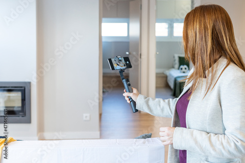 Female real estate agent making a video with her gimbal to show it to her clients in a video call or to upload it to social networks and promote the sale of a property or a property for sale.  photo