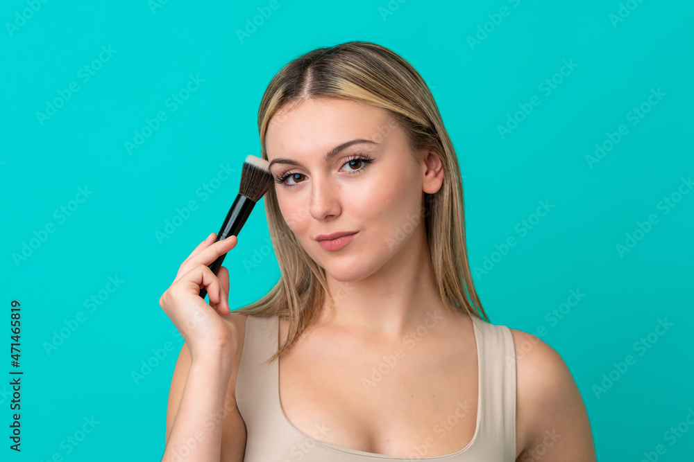 Young caucasian woman isolated on blue background holding makeup brush Young caucasian woman isolated on blue background holding makeup brush