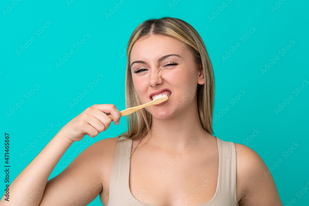 Young caucasian woman isolated on blue background with a toothbrush Young caucasian woman isolated on blue background with a toothbrush