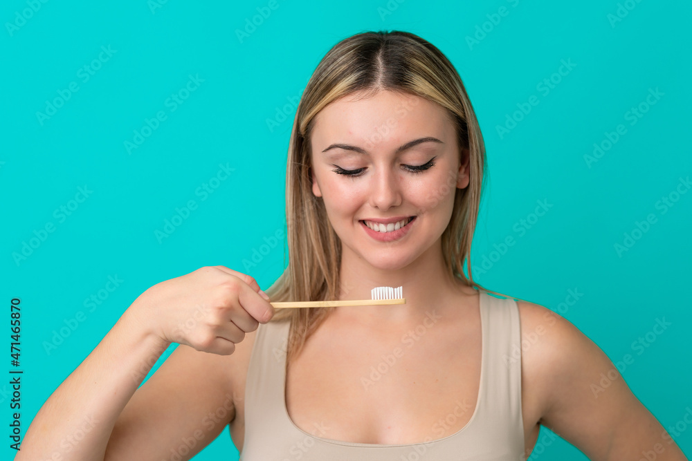 Young caucasian woman isolated on blue background with a toothbrush Young caucasian woman isolated on blue background with a toothbrush