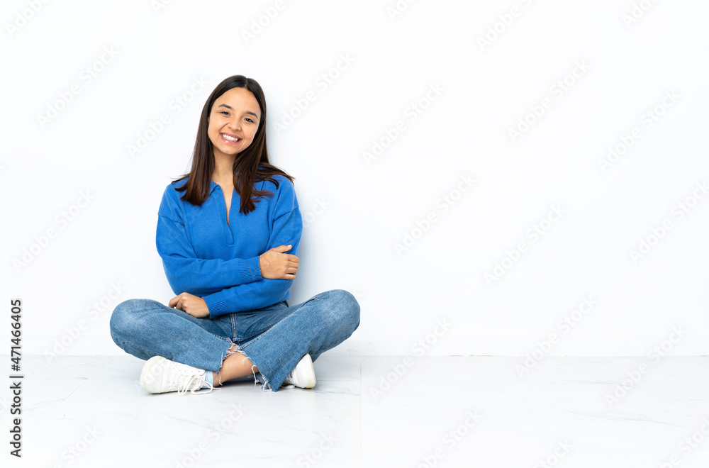 Young mixed race woman sitting on the floor isolated on white background laughing