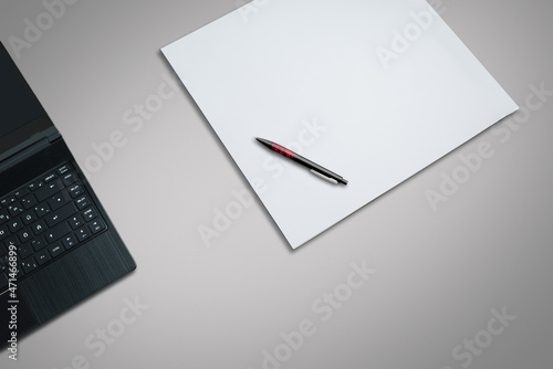 laptop on a desk with  white paper and pen