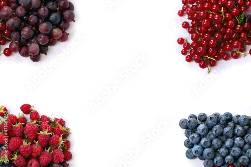 Fresh red berries raspberries, blueberry, redcurrants, dark red gooseberry on white background with space for text. Top view, flat lay