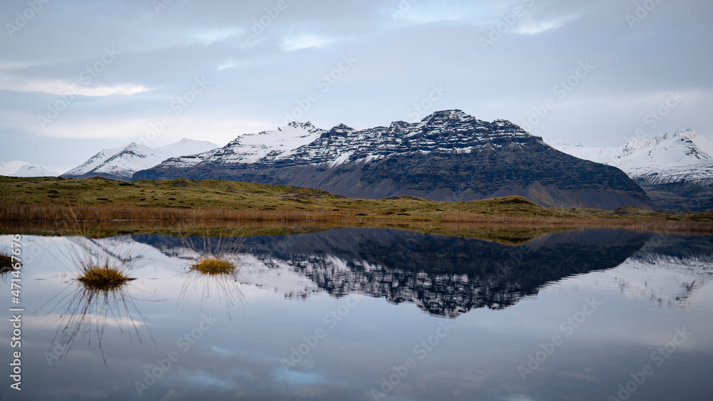 Mountains are reflected in the placid waters around lava fields crossed by a road in East Iceland landmark