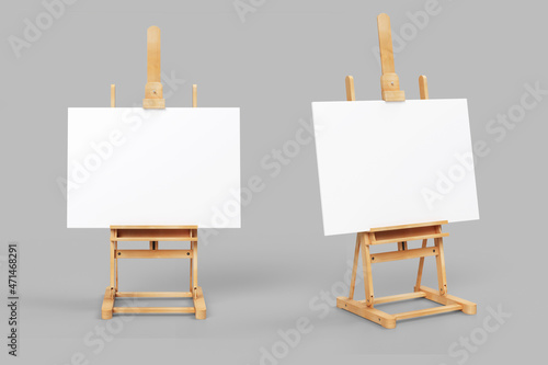 Easel stand board with blank white poster isolated. Wooden easel art painting paper frame stand or poster.White easel stands next to bright grey wall, 3d rendering. 