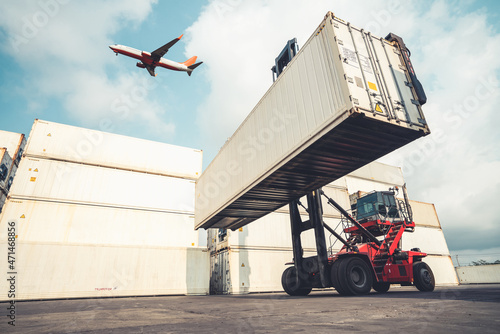 Cargo container for overseas shipping in shipyard with airplane in the sky . Logistics supply chain management and international goods export concept .