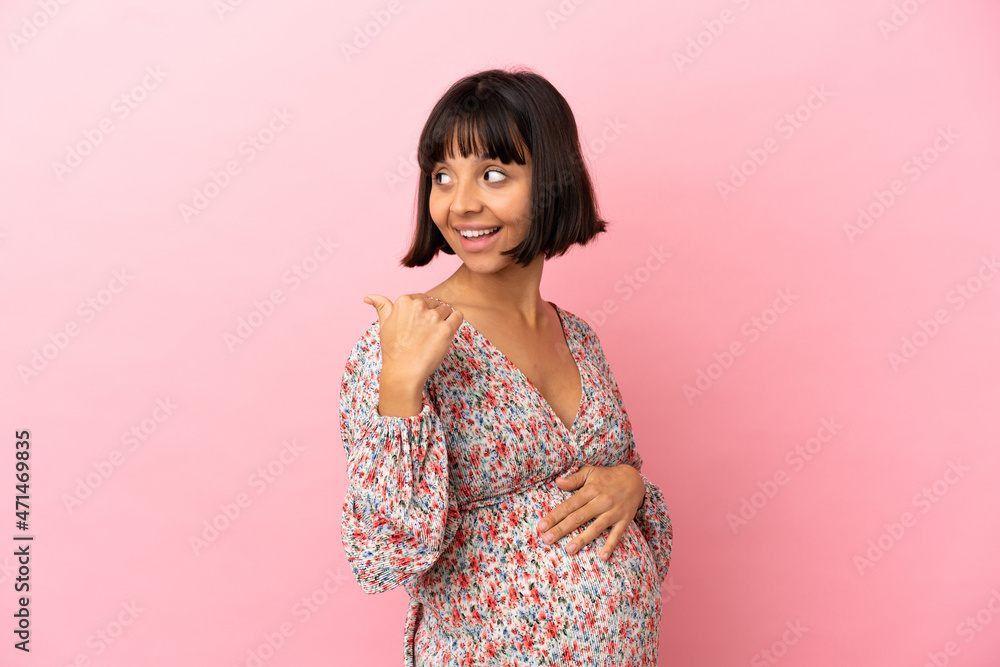 Young pregnant woman over isolated pink background pointing to the side to present a product Young pregnant woman over isolated pink background pointing to the side to present a product