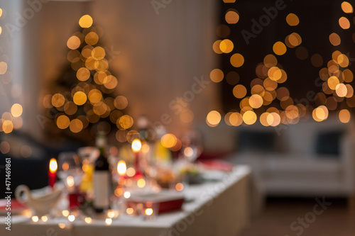 winter holidays and celebration concept - blurred lights and table served for christmas dinner party at home